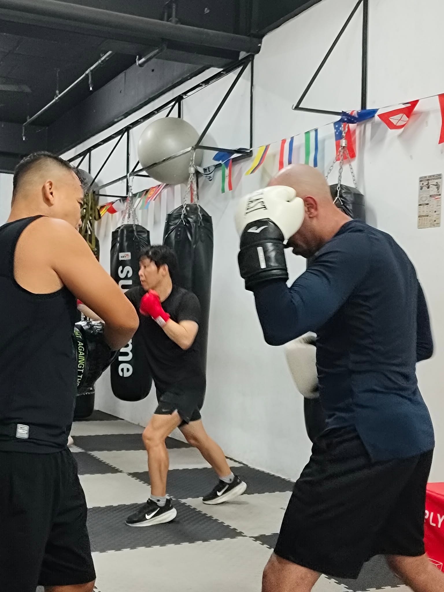 Boxing drills with a coach beside the heavy bags