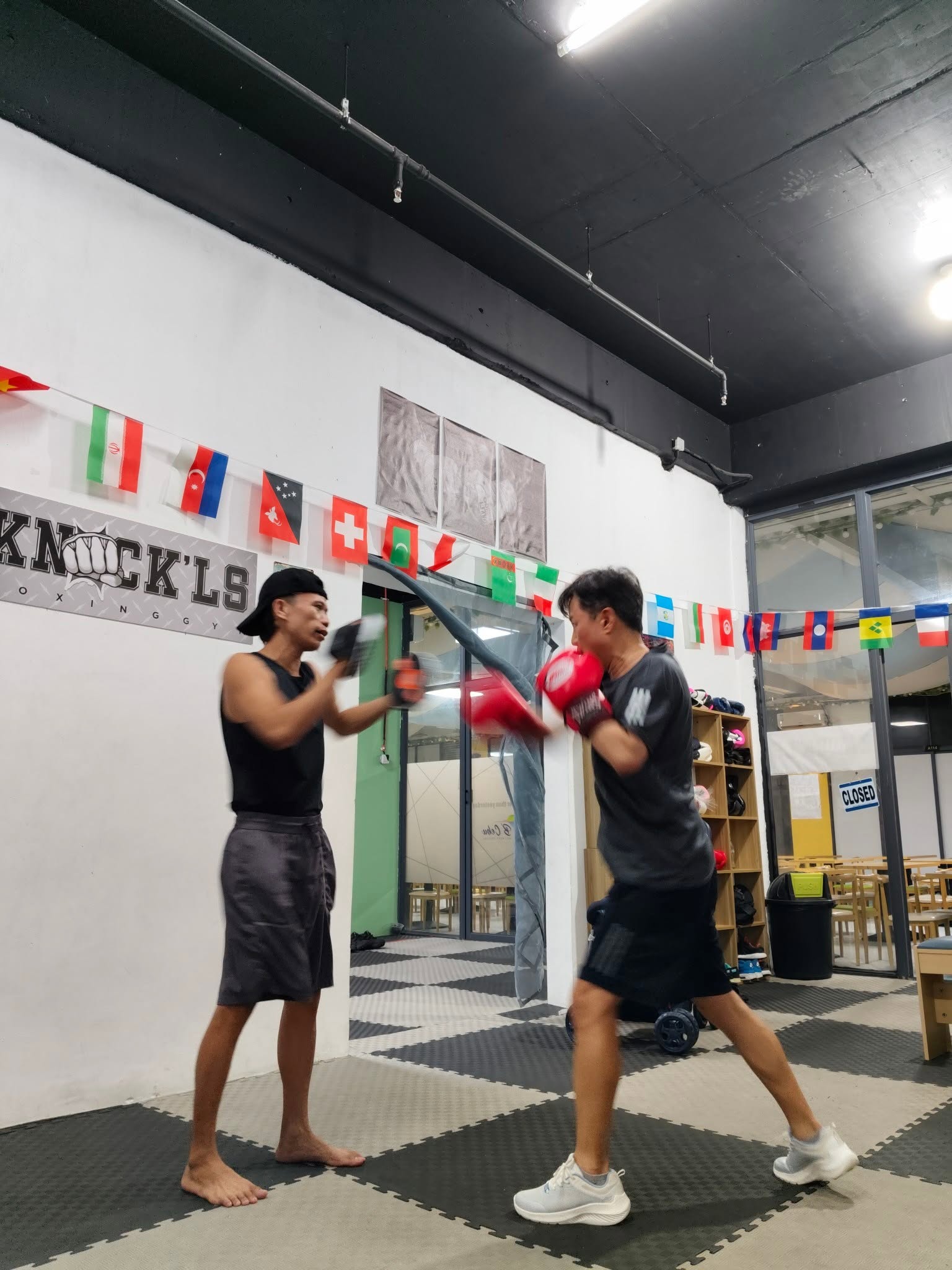 Pad work with a coach in front of the Knock'ls gym sign
